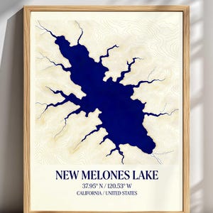 May include: A framed print of New Melones Lake in California, USA. The lake is depicted in a deep blue color, with a detailed topographic map in beige. The text "NEW MELONES LAKE" is displayed below the map, along with the coordinates and location.