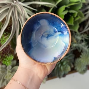 Może przedstawiać: Mała ceramiczna miska z niebiesko-białym marmurowym szkliwem. Miska ma jasnobrązowy rant.