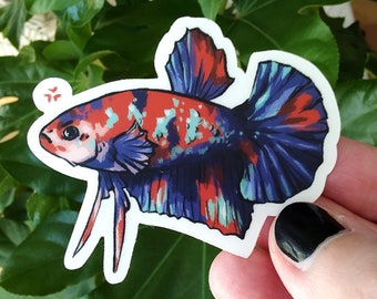May include: A colorful sticker featuring a betta fish with red, blue, and green scales. The fish has a long, flowing tail and is depicted in a swimming pose.