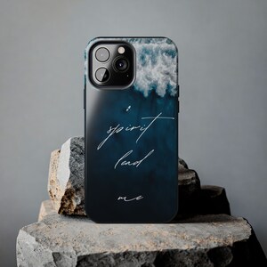 May include: A black phone case with a blue and white ocean wave design. The text "spirit lead me" is written in white on the case.
