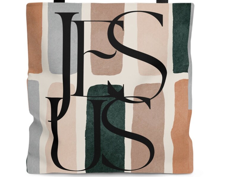 May include: A tote bag with a white background and abstract shapes in shades of brown, green, and gray. The word "JESUS" is written in black script over the shapes.