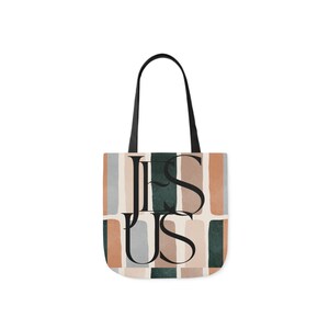 May include: A beige tote bag with black straps and a geometric pattern of brown, beige, and green rectangles. The word "JESUS" is printed in black letters on the bag.