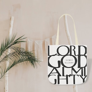 以下が含まれることがあります： 黒い文字で「LORD GOD ALMIGHTY YWHW ELOHIM」と書かれた白いトートバッグ。