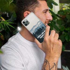 May include: A white phone case with a mountain scene and the text "Faith can move mountains" in black. The case has a clear camera lens.