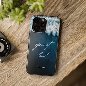 May include: A blue and white phone case with a watercolor-style design of clouds and waves. The text "spirit lead me" is written in white cursive on the case.