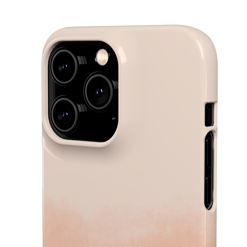 May include: A light beige phone case with a gradient design that fades to a peach color at the bottom. The case has a raised camera bump with three black camera lenses.