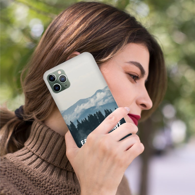 May include: A white phone case with a mountain and forest scene and the text "Escape & Explore". The phone case has a camera lens cutout.