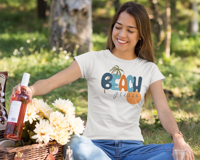 May include: A white t-shirt with a blue, orange, and green graphic that says "Beach Please" with palm trees.