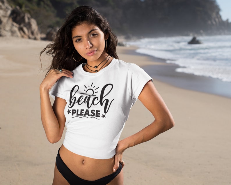 May include: White crop top with a black graphic that says "beach please" with a sun and waves design.