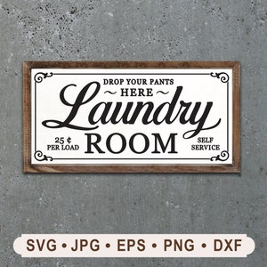 Op de afbeelding: Een wit bord met zwarte tekst dat "Drop your pants here - Laundry Room - 25¢ per load - Self Service" zegt. Het bord is ingelijst met hout en heeft decoratieve krulwerk.