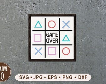 May include: A wooden sign with a tic-tac-toe board featuring game controller symbols. The board has a blue triangle, red circle, and blue X in the top row. The middle row has a pink square, the text "GAME OVER", and a blue triangle. The bottom row has a blue X, a pink square, and a red circle.