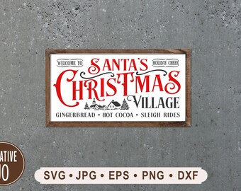 Può includere: Un cartello di legno con sfondo bianco e lettere nere che recita "Benvenuti al Villaggio di Natale di Babbo Natale, Pan di zenzero, Cioccolata calda, Gite in slitta". Le parole "Villaggio di Natale di Babbo Natale" sono in rosso.