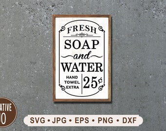 May include: A vintage-style sign with a white background and black text that reads "FRESH SOAP and WATER HAND TOWEL EXTRA 25¢". The sign is framed in wood.