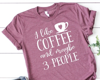 May include: A maroon t-shirt with the text "I like coffee and maybe 3 people" in white lettering. A coffee cup with a heart is included in the text.