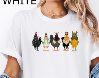 Puede incluir: Camiseta blanca con un gráfico de cinco pollos con gorros de Navidad y luces. Los pollos están en fila, mirando hacia adelante. El texto "WHITE" está en la esquina superior izquierda de la imagen.