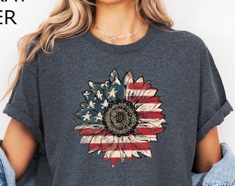 Puede incluir: Camiseta gris oscuro jaspeado con un diseño de girasol con temática de la bandera estadounidense. El girasol tiene rayas rojas y blancas y estrellas azules. El texto "DARK GRAY HEATHER" está en la parte superior de la imagen.