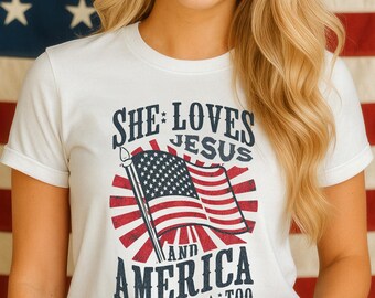 Puede incluir: Camiseta blanca con el texto "She Loves Jesus and America Too" y un gráfico de la bandera estadounidense. El fondo es una bandera estadounidense. La persona está sonriendo.