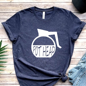 May include: A navy blue t-shirt with a white graphic of a coffee pot and the text "POT HEAD".