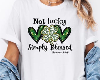 May include: White t-shirt with a green shamrock and two hearts. The text on the shirt reads "Not lucky Simply Blessed Romans 4:7-8".