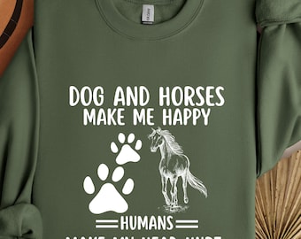 Puede incluir: Sudadera verde militar con el texto "DOG AND HORSES MAKE ME HAPPY HUMANS MAKE MY HEAD HURT". El diseño incluye huellas de patas blancas y una ilustración de un caballo. La sudadera tiene mangas largas y cuello redondo.