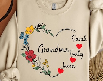 May include: Sand-colored sweatshirt with a floral heart design. The heart is filled with colorful flowers and butterflies, with the word "Grandma" and names "Sarah", "Emily", and "Jason" printed on it. The sweatshirt has a crew neck and long sleeves.