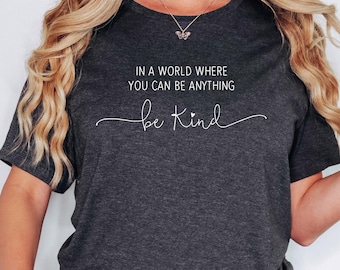 May include: Dark gray heather t-shirt with the text "In a world where you can be anything, be kind" in white lettering.