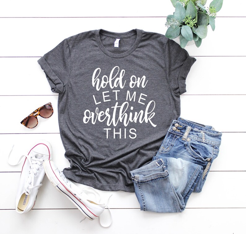 Pode incluir: Uma camiseta cinza escura com o texto "hold on let me overthink this" em letras brancas.