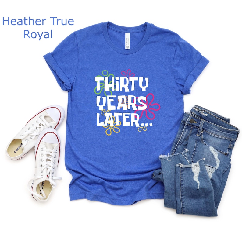 May include: A royal blue t-shirt with the text "Thirty Years Later..." in white with colorful flowers around the text.