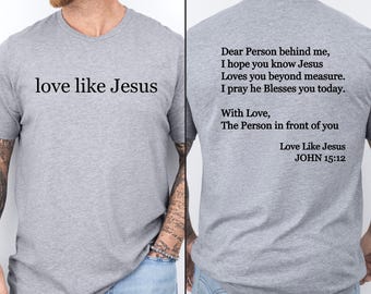 Puede incluir: Camiseta gris con el texto "love like Jesus" en la parte delantera y un mensaje en la parte posterior que dice: "Querida persona detrás de mí, espero que sepas que Jesús te ama más allá de toda medida. Rezo para que te bendiga hoy. Con amor, La persona frente a ti Ama como Jesús JUAN 15:12"