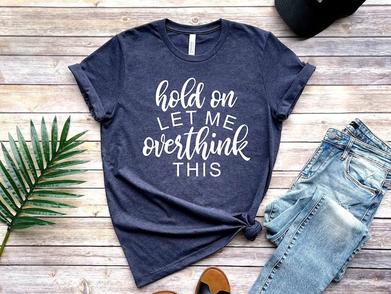 Pode incluir: Uma camiseta azul marinho com o texto "hold on let me overthink this" em letras brancas.