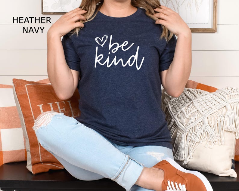May include: A heather navy blue t-shirt with the text "be kind" in white lettering and a small heart graphic above the text.