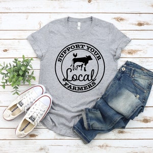 May include: A gray t-shirt with a black circle graphic that says "Support Your Local Farmers" with a cow, chicken, and pig inside the circle.
