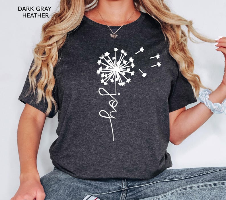 K&ouml;nnte beinhalten: Ein dunkelgraues T-Shirt mit einem wei&szlig;en L&ouml;wenzahnmuster und dem Wort "grow" in Kursivschrift.