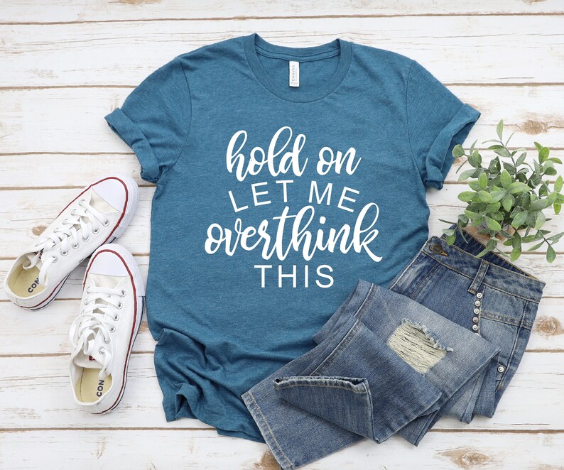 Pode incluir: Uma camiseta azul turquesa com o texto "hold on let me overthink this" em letras brancas.