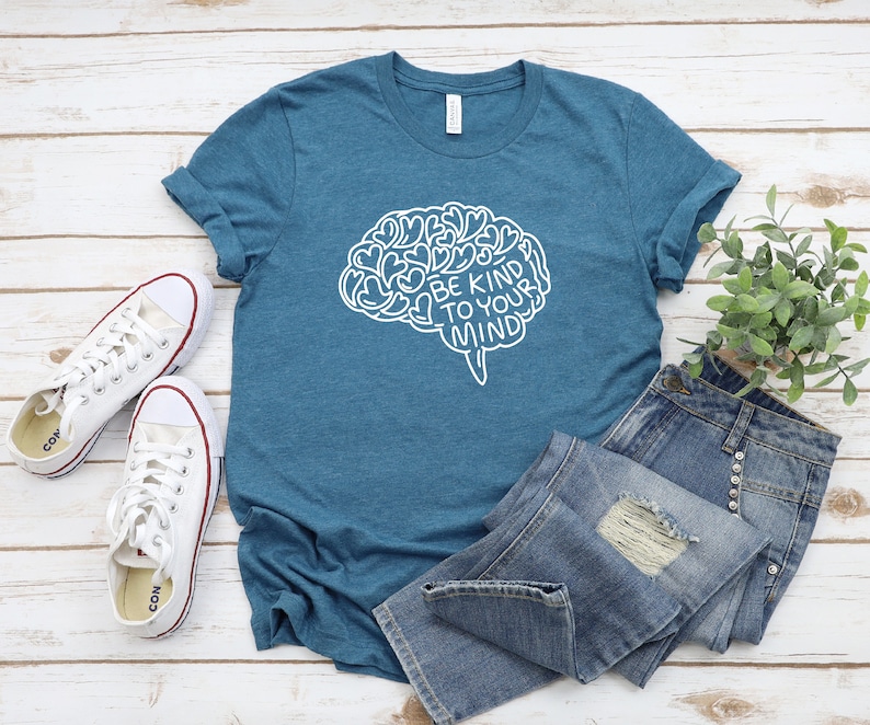 May include: A teal blue t-shirt with a white outline of a brain with hearts inside and the text "Be Kind To Your Mind".