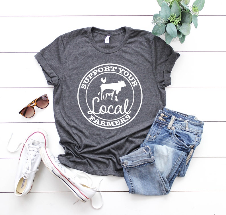May include: A dark gray t-shirt with a white circle graphic that says "Support Your Local Farmers" with a cow, chicken, and calf inside the circle.