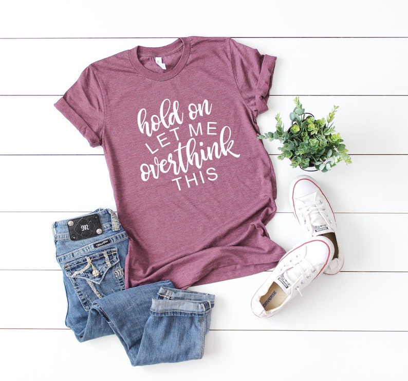 Pode incluir: Uma camiseta de cor vinho com o texto "hold on let me overthink this" em letras brancas.
