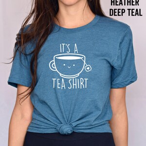 May include: A teal blue t-shirt with the text "It's a Tea Shirt" and a cartoon teacup with a smiling face.