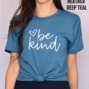 May include: A teal blue t-shirt with a white heart and the text "be kind" printed on the front.