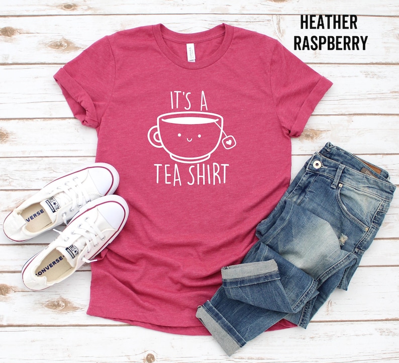May include: A heather raspberry t-shirt with the text "It's a Tea Shirt" and a cartoon teacup with a smiling face.