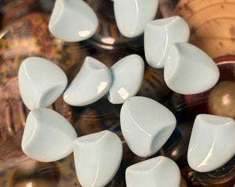 May include: A collection of light blue, rounded, glass-like objects. The objects have a smooth, glossy finish and are arranged among other decorative items. The objects are a soft, pastel blue color.