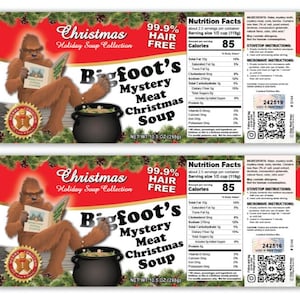 May include: Two soup labels for "Bigfoot's Mystery Meat Christmas Soup." The labels feature a cartoon Bigfoot reading a book, a black cauldron, and the text "Christmas Holiday Soup Collection." Each label is 10.5 oz (298g).