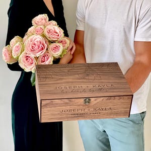 May include: A wooden keepsake box with floral engravings and the names "Joseph + Kayla" and the phrase "two hearts together" engraved on the lid. The box also includes the date "30 JULY | 2023".