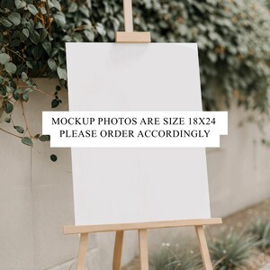 Puede incluir: Un letrero blanco en blanco sobre un caballete de madera, con el texto "MOCKUP PHOTOS ARE SIZE 18X24 PLEASE ORDER ACCORDINGLY". El caballete es de madera clara y est&aacute; colocado al aire libre con vegetaci&oacute;n de fondo.