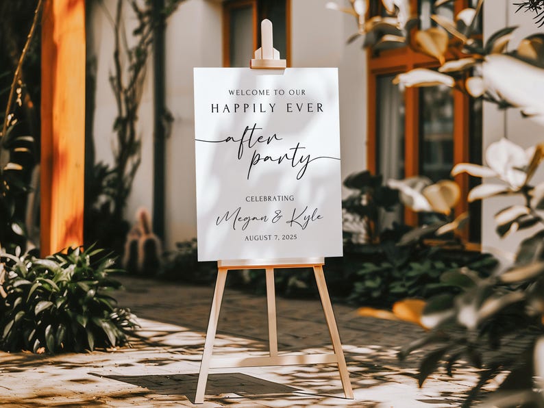 Peut inclure: Un panneau blanc sur un chevalet en bois avec les mots "WELCOME TO OUR HAPPILY EVER AFTER PARTY" en &eacute;criture noire. Le panneau c&eacute;l&egrave;bre Megan & Kyle le 7 ao&ucirc;t 2025. L'arri&egrave;re-plan comprend de la verdure et un b&acirc;timent.