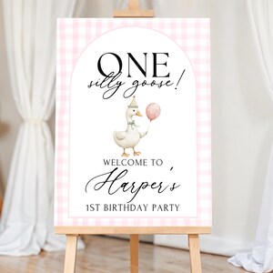 Puede incluir: Un letrero de bienvenida para una fiesta de primer cumplea&ntilde;os. El letrero presenta una ilustraci&oacute;n de acuarela de un ganso con un gorro de fiesta y un globo rosa. El letrero dice "ONE silly goose!" y "Welcome to Harper's 1st Birthday Party."