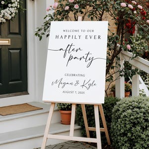 Peut inclure: Un panneau blanc sur un chevalet en bois avec le texte "WELCOME TO OUR HAPPILY EVER AFTER PARTY CELEBRATING Megan & Kyle AUGUST 7, 2025". Le panneau est &agrave; l'ext&eacute;rieur, devant une maison avec une porte verte et des fleurs roses.