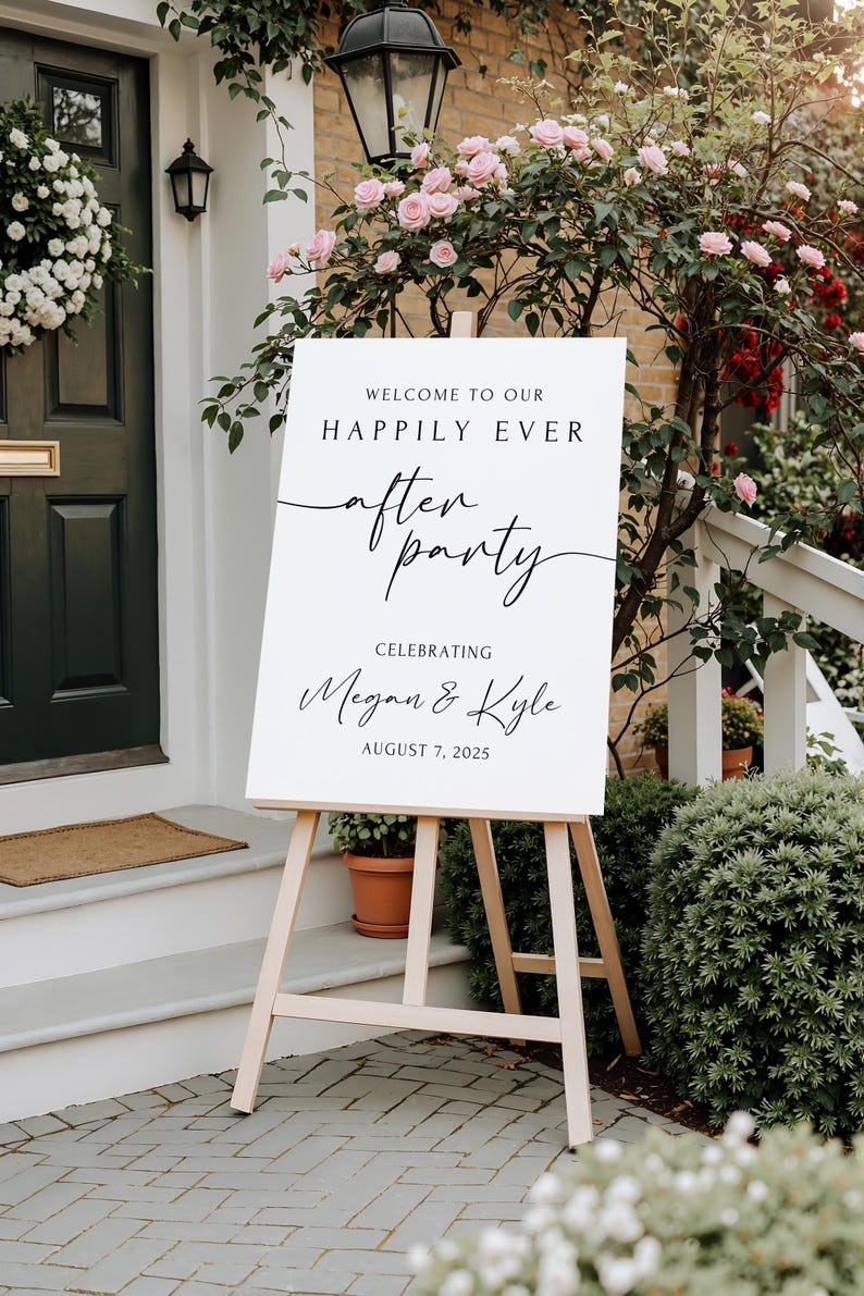 Peut inclure: Un panneau blanc sur un chevalet en bois avec le texte "WELCOME TO OUR HAPPILY EVER AFTER PARTY CELEBRATING Megan & Kyle AUGUST 7, 2025". Le panneau est &agrave; l'ext&eacute;rieur, devant une maison avec une porte verte et des fleurs roses.