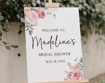 Puede incluir: Un cartel blanco con un diseño floral en la parte superior e inferior. El cartel dice "Bienvenido a Madeline's Bridal Shower el 18 de mayo de 2025".