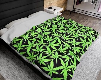 May include: A black and green bedding set with a marijuana leaf pattern. The bedding is on a bed with a white pillow and a black headboard.